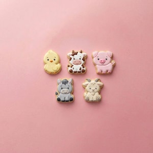 May include: Five farm animal-shaped cookies on a pink background. The cookies include a yellow chick, a brown and white cow, a pink pig, a gray donkey, and a white goat. Each cookie has detailed icing.