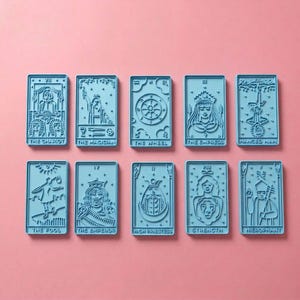 May include: Ten light blue rectangular cookie cutters featuring embossed tarot card designs. The cards include The Chariot, The Magician, The Wheel, The Empress, The Hanged Man, The Fool, The Emperor, The High Priestess, Strength, and The Hierophant.