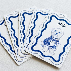 A set of custom playing cards featuring a blue line-art illustration of a dog in a suit with a wavy blue border and the name 'Milo'.
