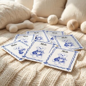 May include: A collection of rectangular white cards featuring a blue ink illustration of a small dog wearing a tuxedo. Each card is bordered by a blue ribbon-style frame and displays the name Milo in cursive script above the dog illustration.