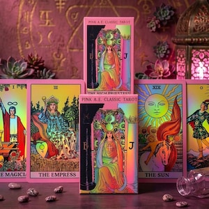 May include: A deck of Pink A.E. Classic Tarot cards featuring vibrant, holographic-style illustrations. The cards display iconic figures like The High Priestess, The Empress, and The Sun, with bold pink borders and clear, legible text labels.