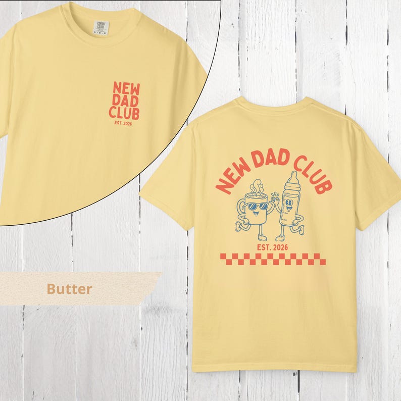 May include: Butter-colored t-shirt with "NEW DAD CLUB" text and graphic on the front and back. The back graphic features a coffee cup and baby bottle with sunglasses, and the text "EST. 2026".