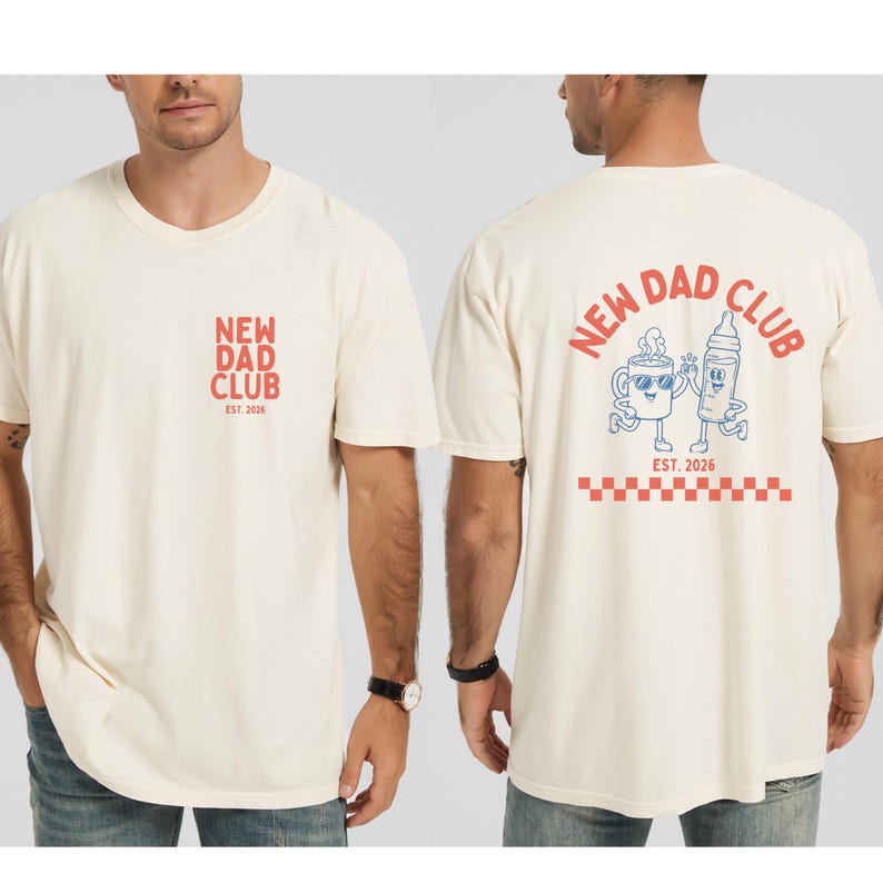 May include: Cream-colored t-shirt with "NEW DAD CLUB" text in red on the front and back. The back features a cartoon coffee cup and baby bottle, with "EST. 2026" below. A red and white checkered pattern is at the bottom.