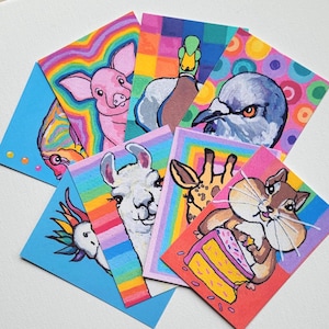 May include: A collection of colorful, hand-painted animal art cards. Each card features a different animal, including a pig, duck, bird, llama, giraffe, and chipmunk, with vibrant rainbow and geometric backgrounds. The cards are on a white surface.