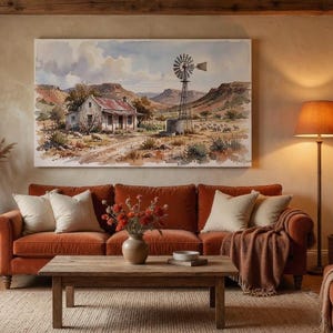 May include: A living room with a rust-coloured sofa, cream cushions, and a wooden coffee table. A watercolour painting of a rural scene hangs above the sofa. A floor lamp with an orange lampshade provides warm lighting.