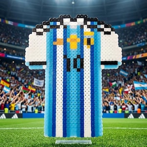 May include: A pixel art style jersey made of small plastic beads featuring vertical light blue and white stripes. The jersey has a yellow emblem on the chest and the number 10 in black. It is displayed on a clear stand against a stadium background.