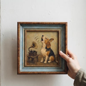 May include: An oil painting in a square, distressed blue and brown wooden frame featuring a beagle dog howling at a vintage gramophone. The dog is brown, black, and white, sitting on a tan floor. The gramophone sits on a small wooden stool.