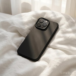May include: A matte black smartphone case featuring a raised square camera module with three circular lenses and a small flash. The case has a smooth, solid-colored surface and rounded corners, designed to fit a modern mobile device securely.