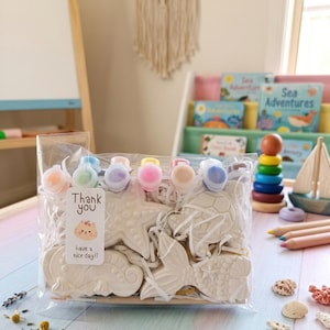 Peut inclure: Un sachet en plastique transparent contenant quatre figurines en céramique blanche sur le thème de la mer, dont une étoile de mer, une tortue, un hippocampe et une queue de sirène. Le kit inclut six petits pots de peinture et un pinceau avec une étiquette Thank you have a nice day.