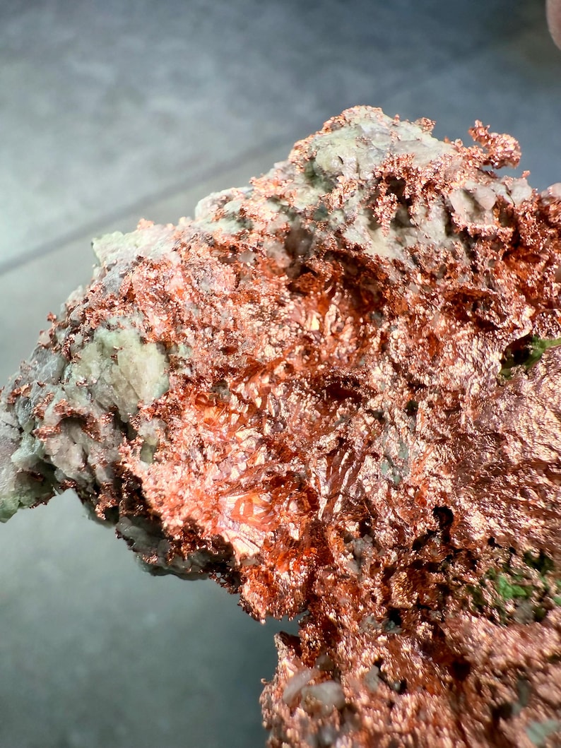 May include: A close-up of a copper ore specimen. The specimen displays a mix of textures and colors, with a prominent display of bright, metallic copper. The copper is layered and textured, contrasting with the lighter, mineral-rich matrix.
