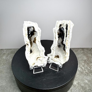 May include: Two white and black agate geodes, displayed on clear stands. The geodes have a crystalline exterior and a dark interior with intricate patterns. The set is labeled "Set 6" in white text.