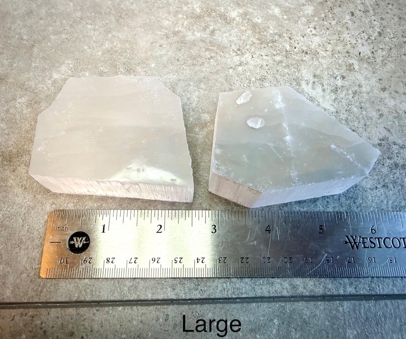 Pu&ograve; includere: Due grandi pietre chiare di forma irregolare sono esposte accanto a un righello. Le pietre sono lunghe circa 7,6 cm. La parola "Large" &egrave; stampata sotto il righello.