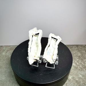 May include: Two white and silver decorative oyster shell pieces, displayed on clear stands. The shells have a textured, natural appearance. The set is labeled "Set 9" in white text.