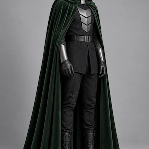 Può includere: Un costume completo composto da un mantello con cappuccio in velluto verde scuro, una maschera facciale in metallo argentato e una tunica nera con pettorina argentata. L'outfit include pantaloni neri, una cintura, bracciali argentati e stivali neri.
