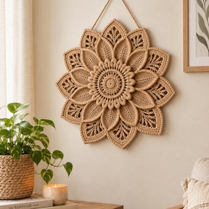 May include: A circular beige crochet wall hanging featuring a layered floral design with intricate leaf-shaped petals radiating from a central point. The piece is suspended by a matching beige cord attached to a small wooden knob on the wall.