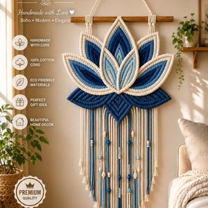 Peut inclure: Une tenture murale en macramé représentant une feuille de lotus dans des tons de bleu marine, bleu clair et crème. L'objet est suspendu à une tige en bois et comporte des brins pendants ornés de perles en bois bleues et crème.
