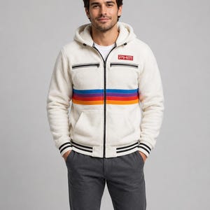 Può includere: Una felpa con cappuccio e zip in pile color crema con un motivo a righe orizzontali blu, viola, rosso e arancione sul petto. Il capo presenta una cerniera nera, due tasche sul petto con zip, un cappuccio e la scritta PHM.
