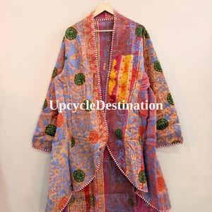 May include: A long-sleeved open-front jacket featuring a patchwork design with various floral and circular patterns in shades of orange, pink, blue, and yellow. The garment includes visible stitching and the text UpcycleDestination printed in white.