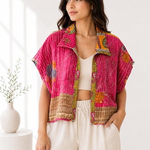 Peut inclure: Une veste à manches courtes ouverte sur le devant, de couleur magenta vif avec des surpiqûres kantha blanches. Le vêtement présente un large col et des panneaux contrastés vert olive et dorés à motifs floraux sur l'ourlet et les bords.