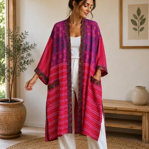 May include: A long, open-front kimono featuring a vibrant magenta and bright pink color palette with a repeating white chevron pattern on the lower section, a floral print on the upper section, wide sleeves, and two front patch pockets.