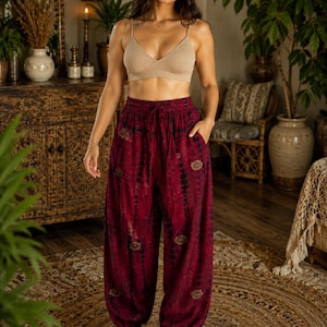 Op de afbeelding: Een beige geribbelde bralette met dunne bandjes gecombineerd met een wijde, donkerrode harembroek met een donker tie-dye patroon, kleine ronde bloemmotieven, een elastische tailleband met trekkoord en elastische boorden bij de enkels.
