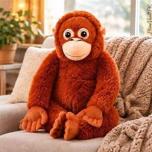 May include: A plush orangutan toy with shaggy, rust-coloured fur, a smooth beige face, and large dark eyes. The stuffed animal is seated in an upright position with flat, textured hands and feet. The text PrimeVaultPK is visible in the corner.