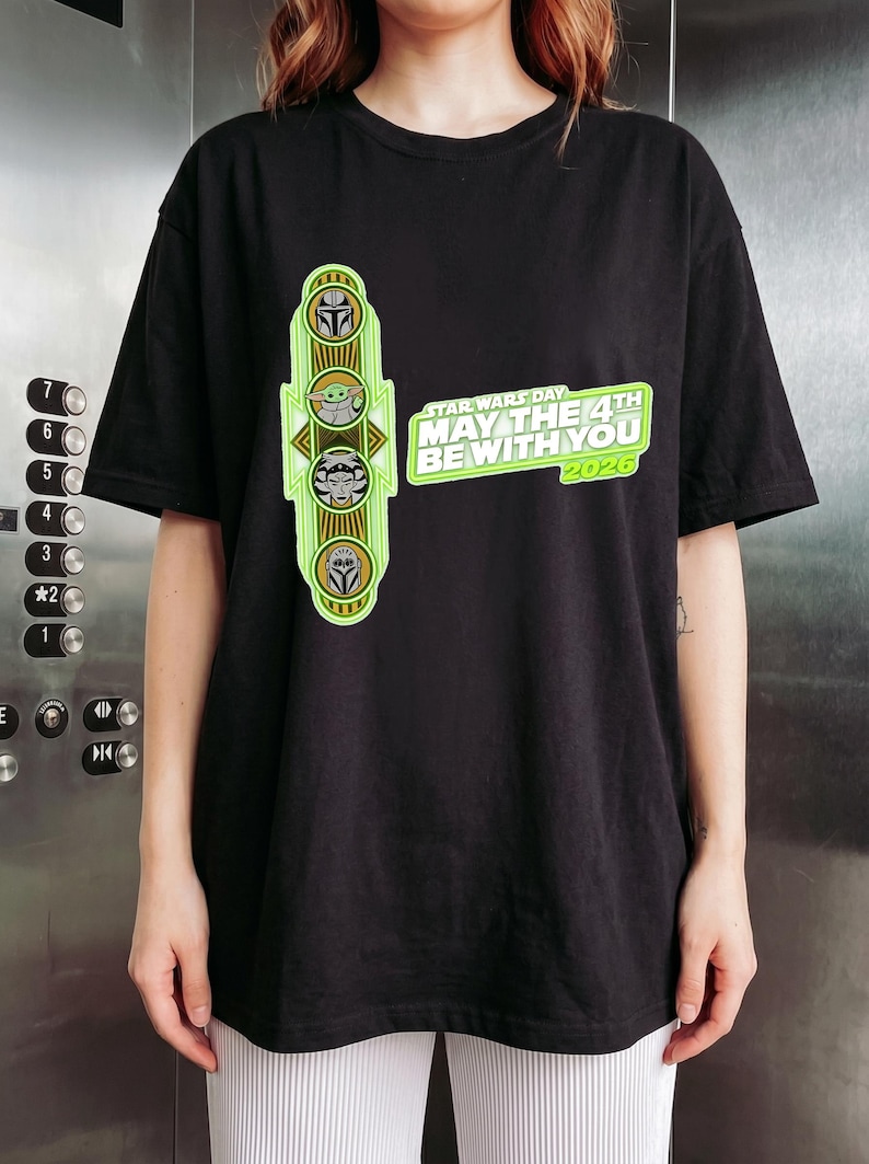 Pu&ograve; includere: T-shirt nero con un design del Star Wars Day. Il design include illustrazioni di personaggi e la scritta "MAY THE 4TH BE WITH YOU 2020". La grafica &egrave; verde e gialla. Un capo d'abbigliamento casual.