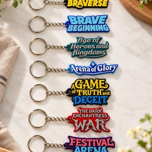 May include: A set of seven colorful rubber keychains with metal rings and chains. Each keychain features unique text: CookieRun BRAVERSE, BRAVE BEGINNING, Age of Heroes and Kingdoms, Arena of Glory, A GAME of TRUTH and DECEIT, THE DARK ENCHANTRESS WAR, and FESTIVAL ARENA.