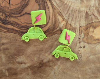 May include: A pair of green and pink earrings featuring a small car charm with a lightning bolt charm hanging from it.