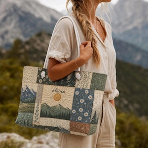 May include: A quilted tote bag featuring a patchwork design with mountain landscapes, pine forests, and daisy floral patterns. The center panel displays a sunburst motif above a mountain range with the name olivia embroidered in black script.