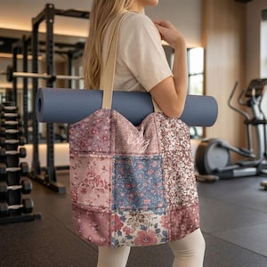 May include: A floral patchwork tote bag with a beige strap, holding a rolled-up blue yoga mat. The bag features various floral patterns in shades of pink, blue, and brown. The word "lily" is embroidered on the front. The background shows a gym setting with exercise equipment.