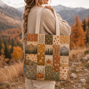 May include: A quilted tote bag featuring a patchwork design of rectangular panels. The fabric displays autumn-themed prints including mountain landscapes, pine forests, orange pumpkins, maple leaves, and various floral patterns in earthy tones.