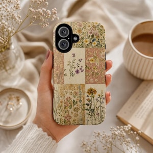 May include: A rectangular smartphone case featuring a grid of six distinct panels, each decorated with various pressed wildflower illustrations in shades of yellow, purple, green, and cream, with a black camera cutout in the upper left corner.