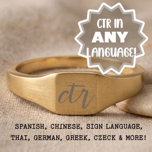 May include: A gold-colored signet ring with a rectangular face. The face of the ring has the letters "ctr" engraved in a cursive font. The image also contains the text "CTR IN ANY LANGUAGE!" and a list of languages.