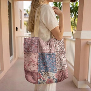 May include: A patchwork tote bag with a beige strap. The bag features a variety of floral patterns in shades of pink, blue, and brown. The word "lily" is embroidered on the front of the bag.