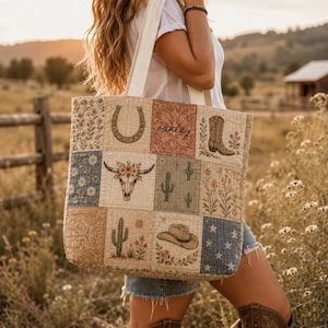 May include: A quilted tote bag featuring a patchwork design with various illustrations including a horseshoe, a cow skull, cacti, a cowboy hat, and a boot. The bag includes the name Oakley in cursive script and has two white fabric shoulder straps.