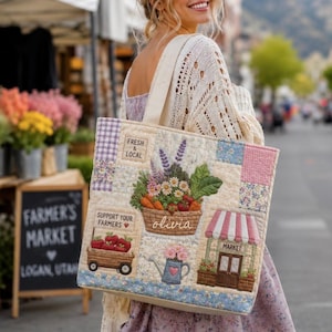 May include: A quilted tote bag featuring embroidered patches of a vegetable basket, a wagon with apples, a watering can with flowers, and a market stall. The text reads Fresh & Local, Support Your Farmers, Olivia, and Market.