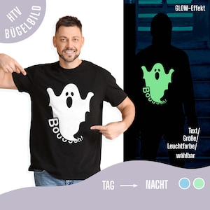Könnte beinhalten: Ein schwarzes Kurzarm-T-Shirt mit einer weißen Geistergrafik und dem darunter gedruckten Text "Booooooh!". Das Motiv ist so gestaltet, dass es im Dunkeln leuchtet und nachts als hellgrüne Silhouette vor einem dunklen Hintergrund erscheint.