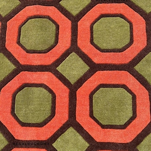 May include: A tufted rug featuring a repeating geometric pattern of orange octagons and olive green diamonds outlined in dark brown. The text REGALRUGHOME is visible in small black letters within the pattern on the rug surface.
