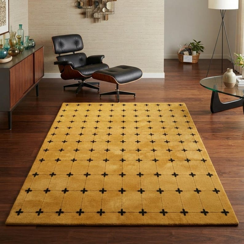 May include: A rectangular area rug featuring a solid mustard yellow background with a repeating grid pattern of thin black lines and small black cross symbols at each intersection, covering the entire surface of the floor covering.