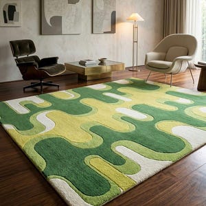 May include: A large, rectangular area rug with a vibrant, abstract design. The rug features a pattern of flowing, organic shapes in shades of green, yellow, and white. The rug is placed on a dark wood floor, and the room has a modern aesthetic.