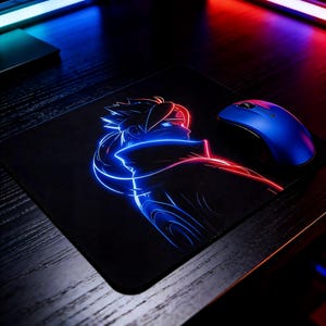 May include: Black rectangular mouse mat featuring a neon-style illustration of a character in red and blue. A blue wireless mouse sits to the right of the mat. The desk is dark wood.