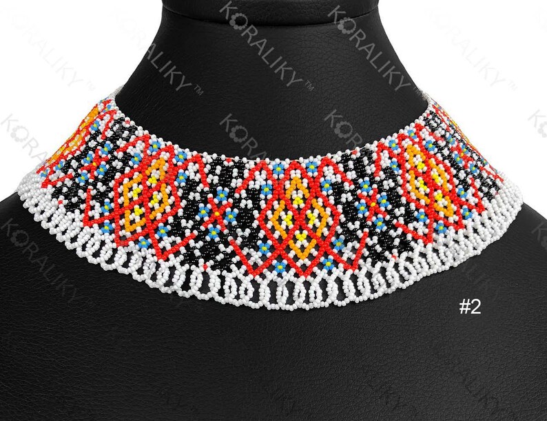 May include: A colourful beaded choker necklace with a geometric pattern. The necklace features red, yellow, blue, and black beads on a white beaded base. The necklace is displayed on a black mannequin.