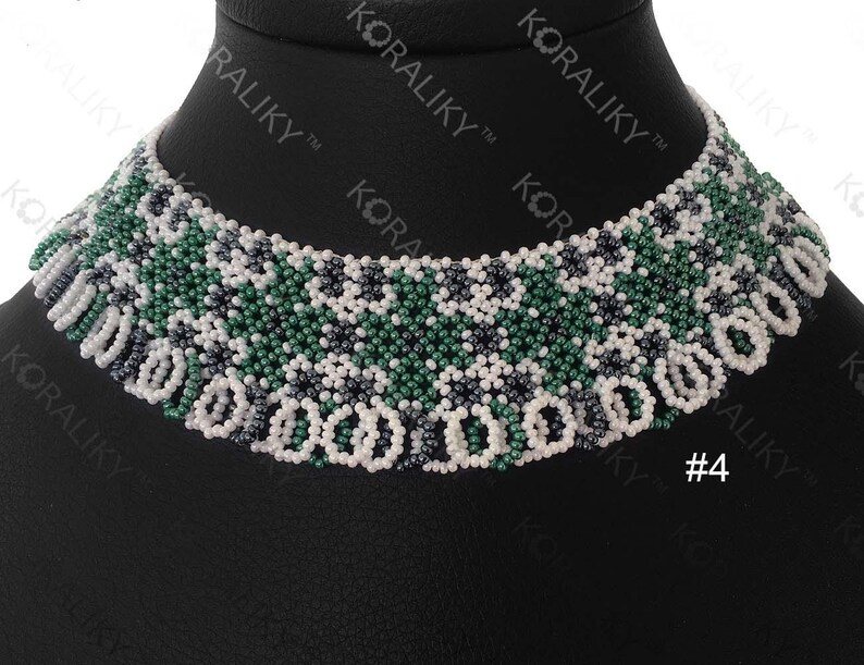 May include: A white, green, and black beaded choker necklace. The necklace has a geometric pattern and is displayed on a black mannequin.