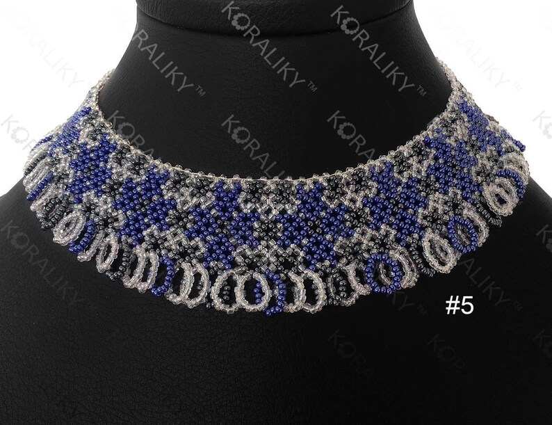 May include: A beaded necklace with a geometric pattern in shades of blue, gray, and white. The necklace is on a black background and has a fringe-like design at the bottom. #5