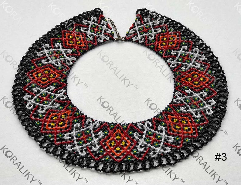 May include: A collar necklace crafted from beads, featuring a black background and detailed patterns in red, white, yellow, and green. The design incorporates geometric and floral motifs. The text "#3" is visible on the bottom right.