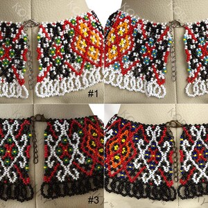 May include: Four beaded collar necklaces with detailed patterns. Each necklace uses red, white, black, and yellow beads. The necklaces are displayed on a mannequin, highlighting their design and craftsmanship. The necklaces are approximately 15 cm in length.