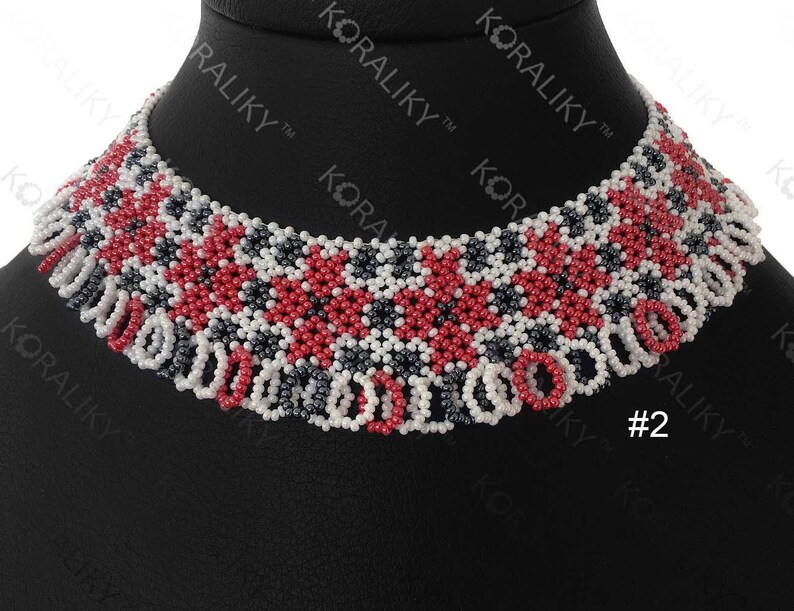 May include: A red, white, and black beaded necklace with a geometric pattern. The necklace is on a black display stand. #2