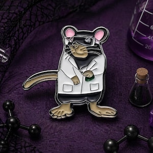 May include: A metal pin featuring a cartoon rat wearing a lab coat and glasses. The pin is black, white, and tan with pink ears. The background includes laboratory equipment and a purple dice.