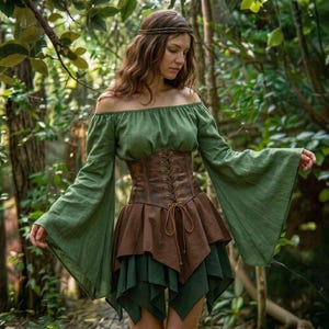 Könnte beinhalten: Ein grünes schulterfreies Oberteil mit ausgestellten Ärmeln, kombiniert mit einem braunen Korsett und einem mehrschichtigen Rock. Der Rock hat eine braune obere Schicht und eine grüne Unterschicht. Ein braunes Stirnband vervollständigt den Look.